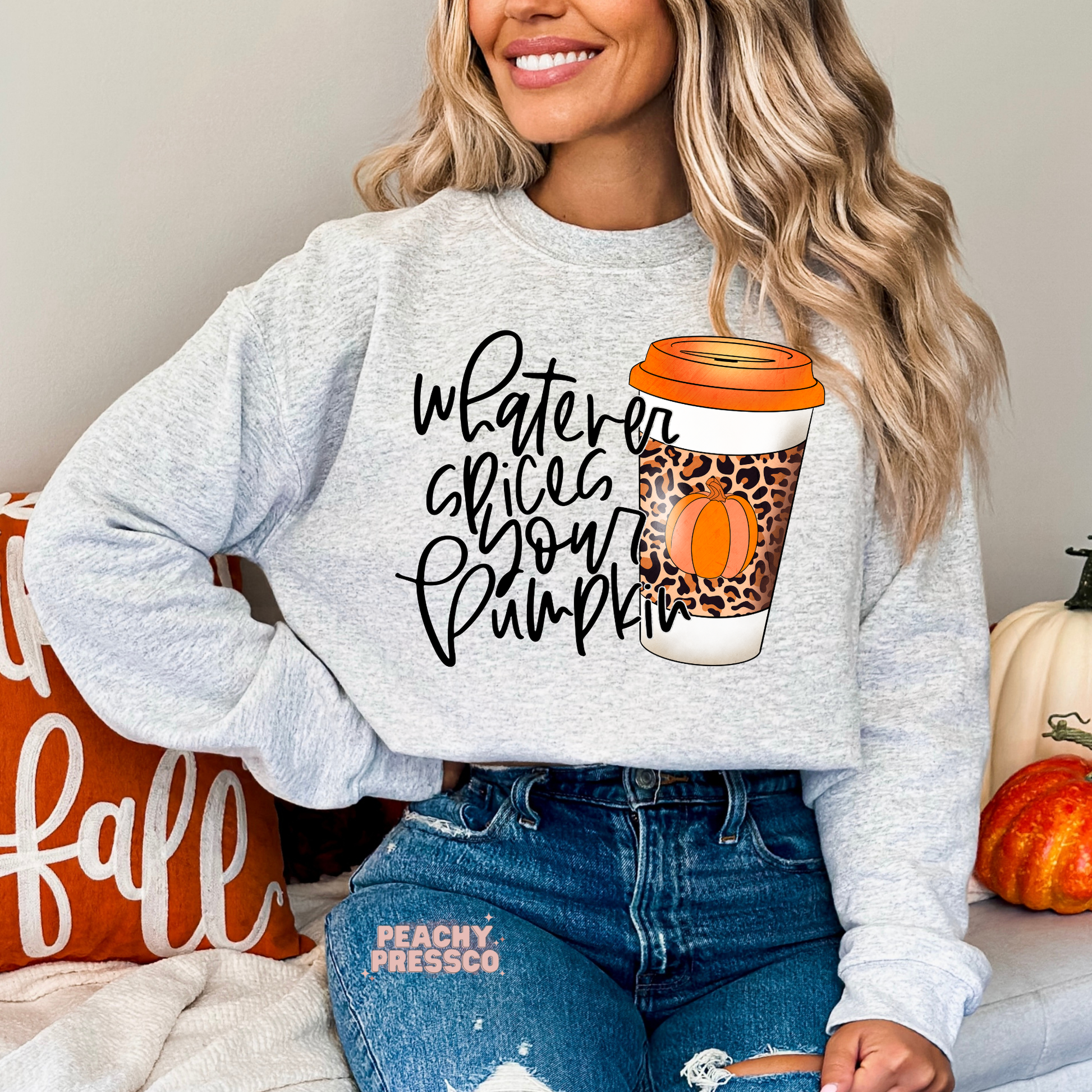 Woman wearing an ash grey sweatshirt displaying a cute "Whatever Spices Your Pumpkin" autumn design with a leopard print pumpkin spice coffee cup.