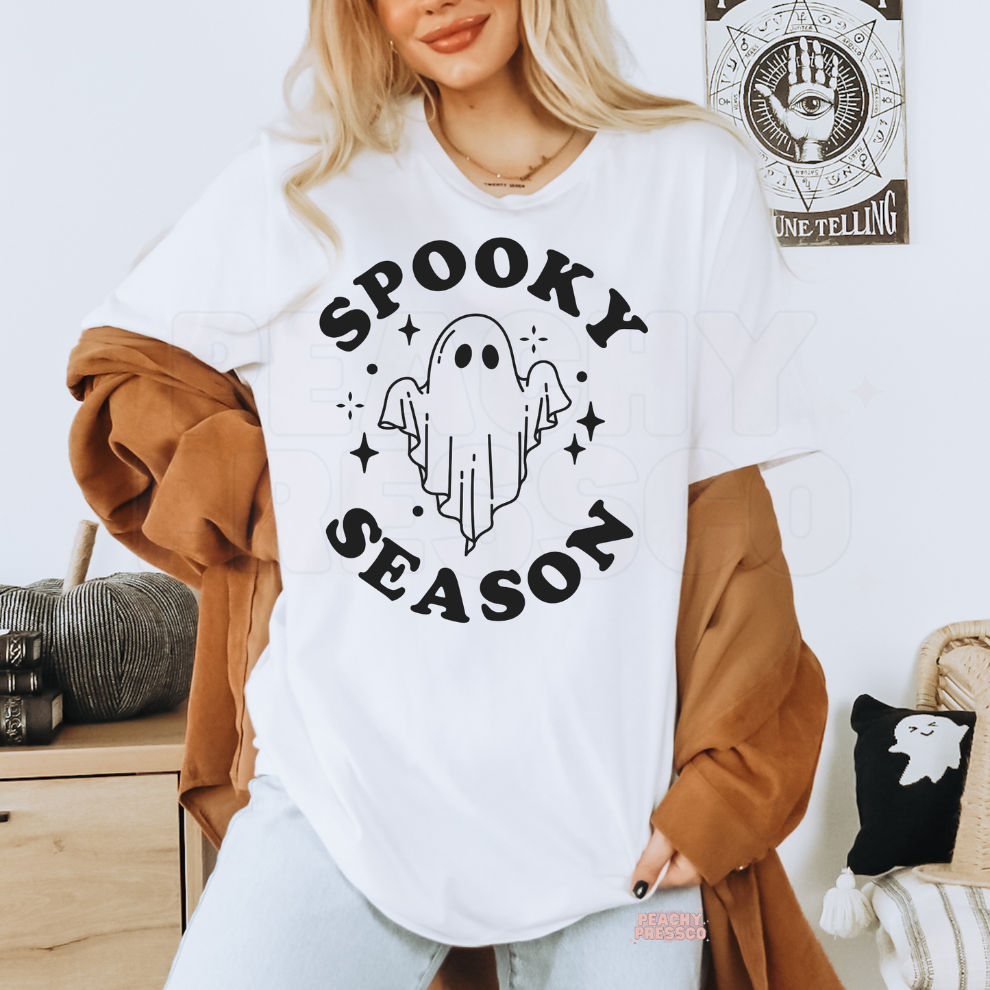 Woman wearing a white Spooky Season ghost Halloween t-shirt with a minimalist ghost graphic.