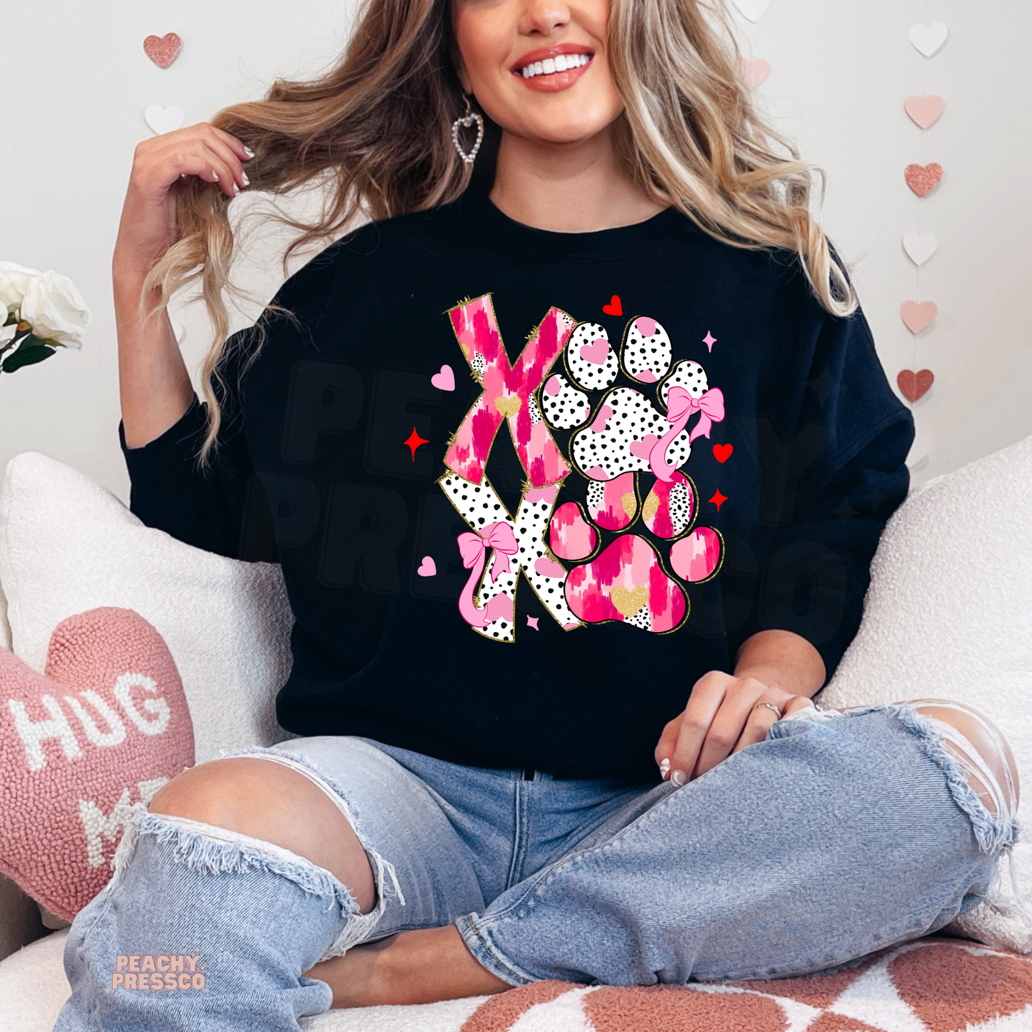 Black crewneck sweatshirt featuring a vibrant pink XOXO dog paw graphic with playful hearts and bows for dog moms.