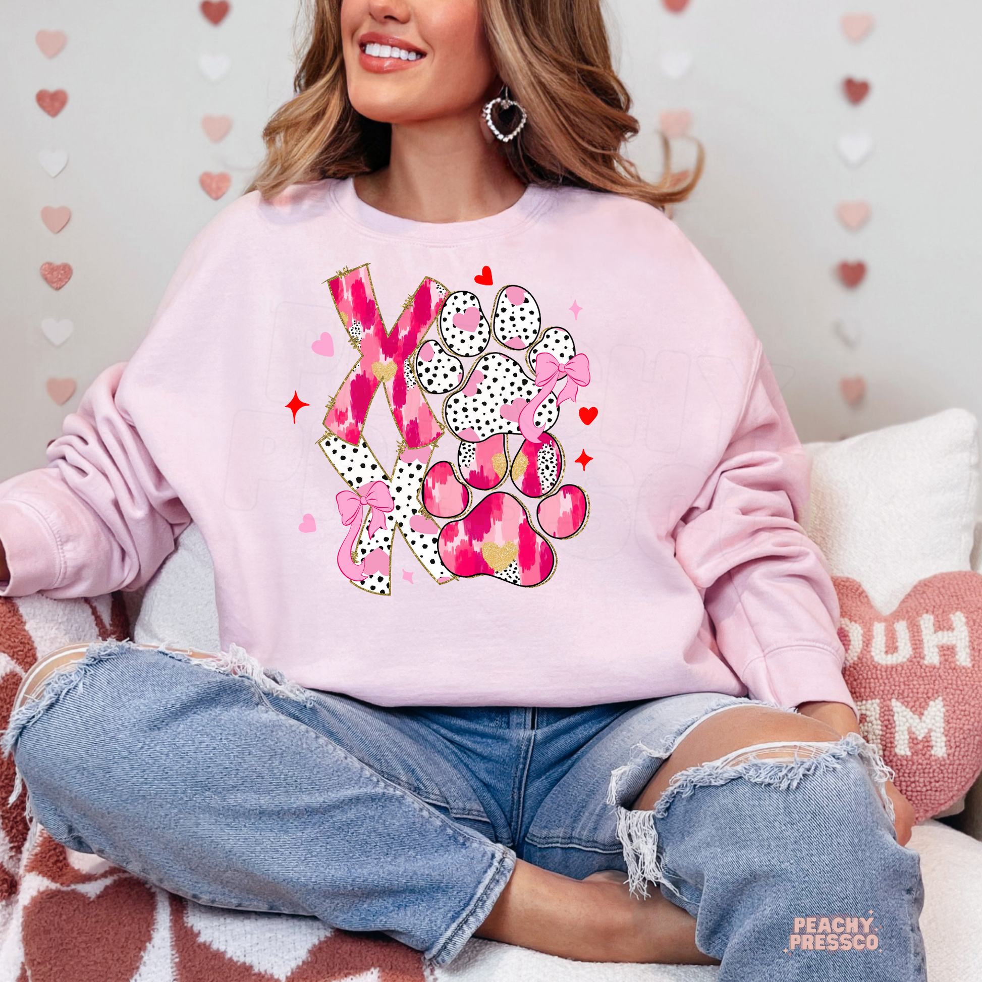 Light pink sweatshirt showcasing a cute XOXO dog paw design with pink bows, hearts, and leopard-inspired details, perfect for Valentine's Day dog moms.