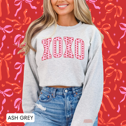 Ash grey crewneck sweatshirt with oversized XOXO varsity letters filled with red hearts for a trendy Valentine's Day outfit.