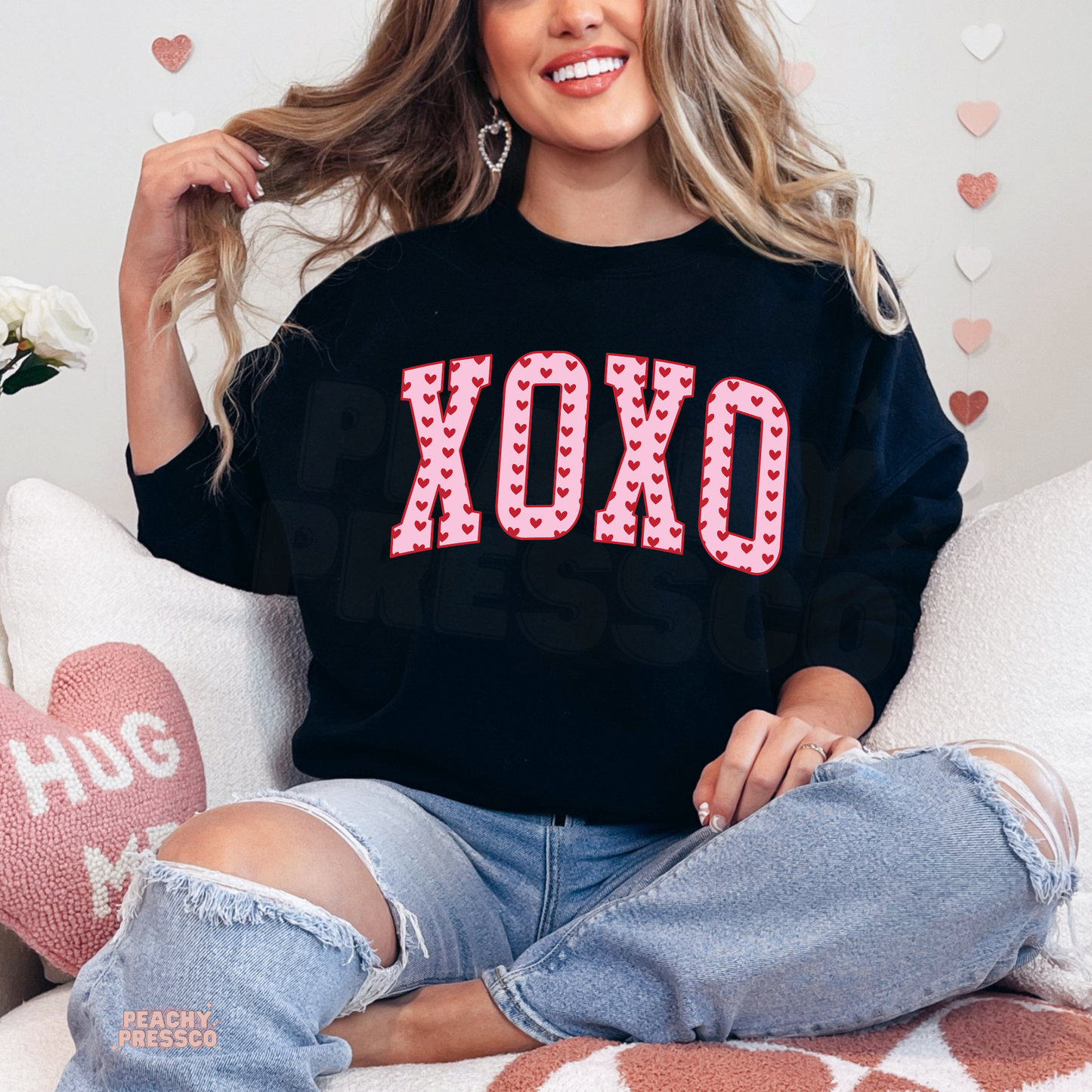 Bold XOXO Valentine's graphic on a black crewneck sweatshirt featuring oversized varsity letters with red heart pattern.