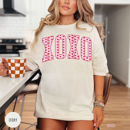 Retro XOXO heart graphic displayed on an ivory unisex t-shirt with varsity-style lettering and Valentine's Day aesthetic.