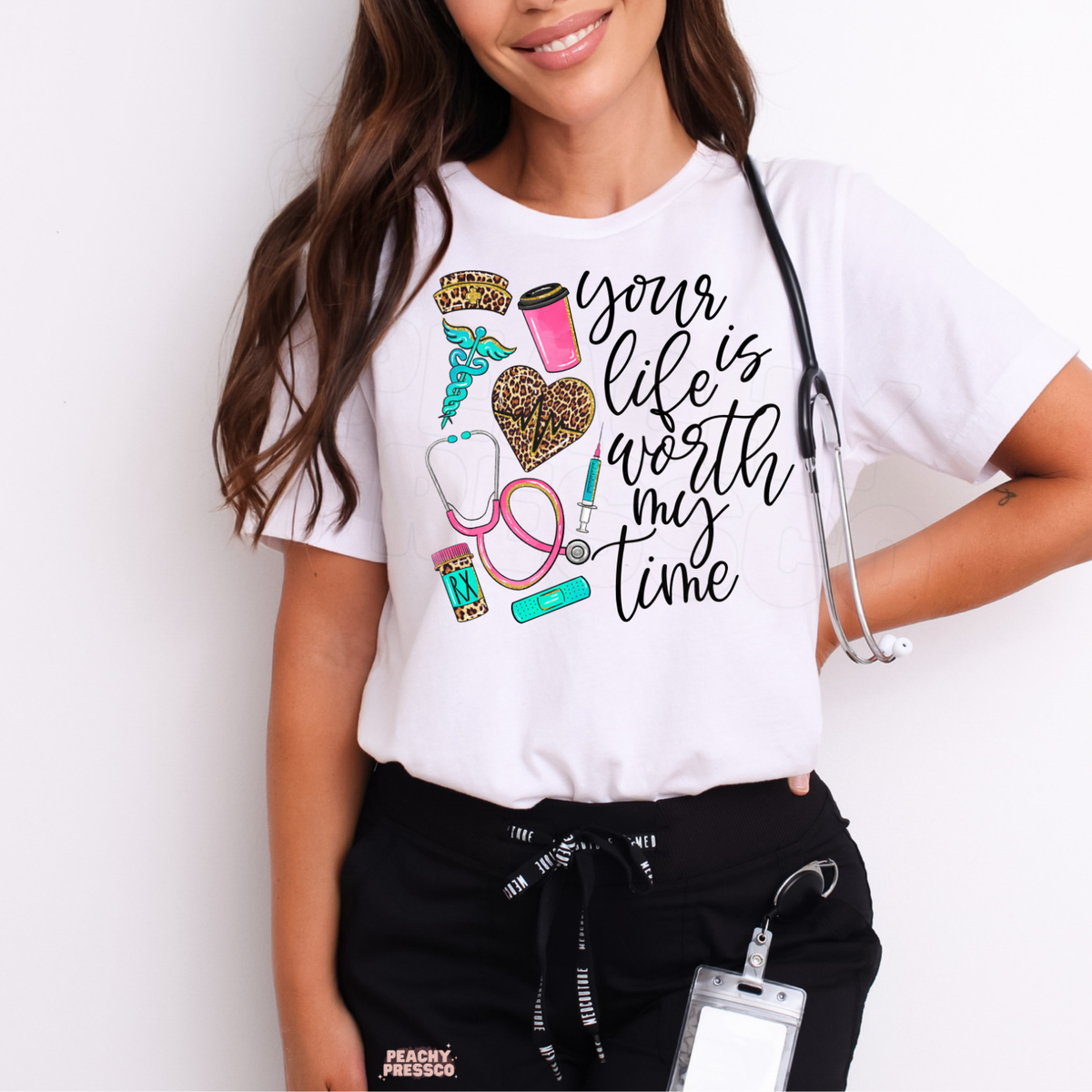 White nurse T-shirt featuring Your Life Is Worth My Time script, leopard print heartbeat heart, pink stethoscope, syringe and nursing icons.