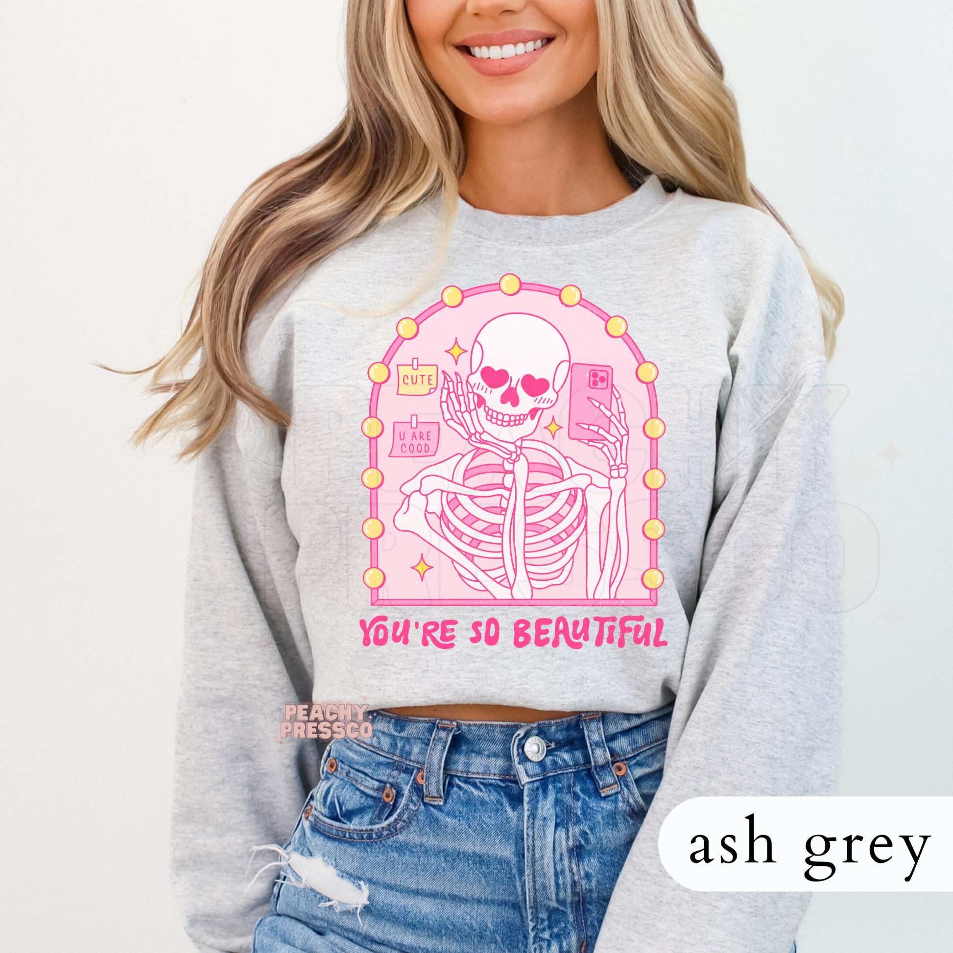 Ash grey sweatshirt featuring a pink coquette skeleton selfie illustration with heart eyes, vanity mirror, and "You're So Beautiful" graphic.