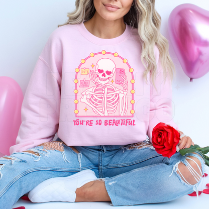 Light pink sweatshirt with a kawaii pink skeleton mirror selfie design featuring heart eyes and "You're So Beautiful" lettering.